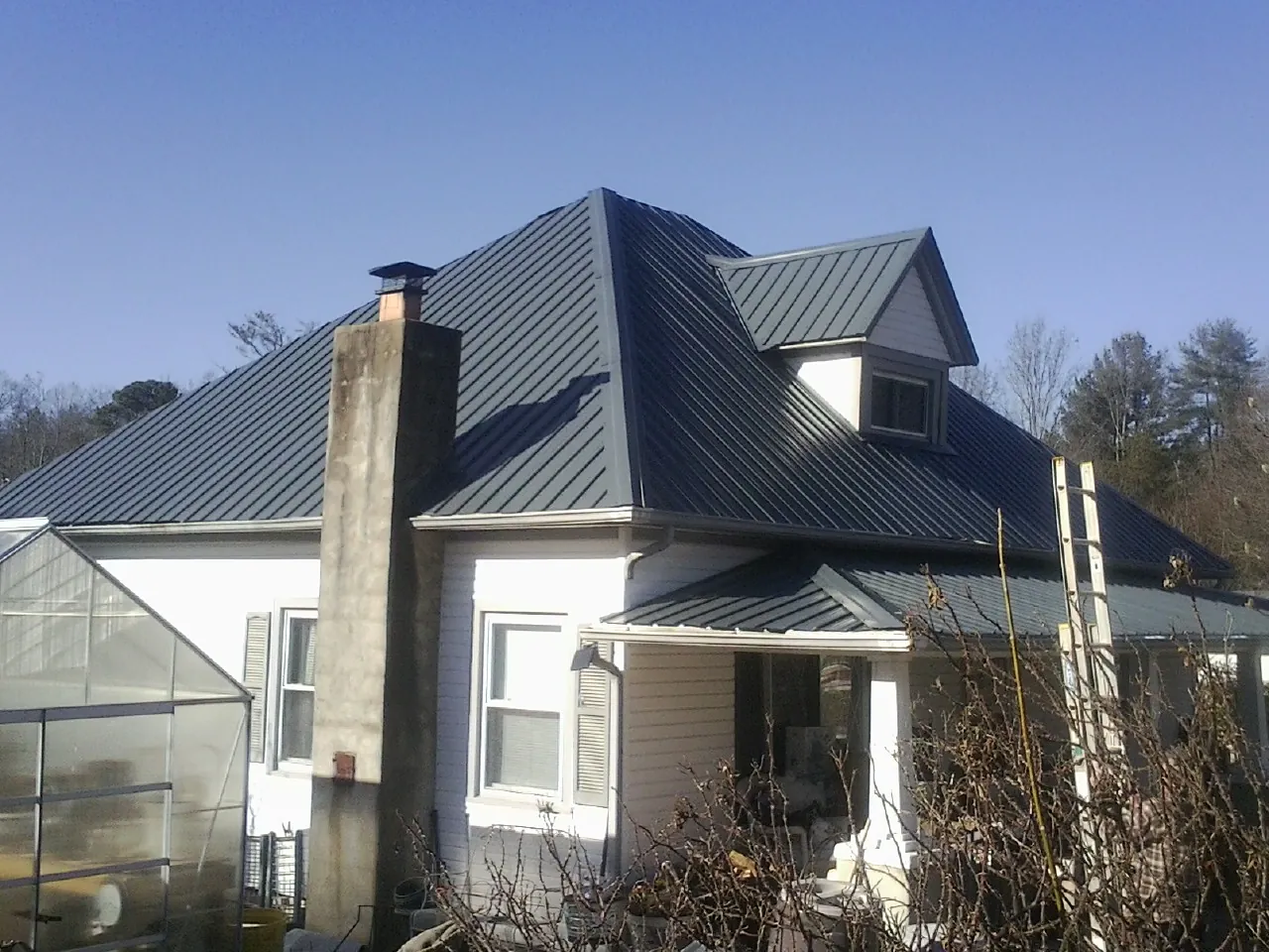 Dark blue standing seam metal roof on a white farmhouse with dormer — Slate & Tile Roof Repair by Roofing Brothers in Nellysford
