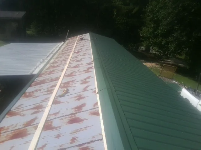 Old rusted panels beside newly installed green metal roofing — Wind Damage Roof Repair by Roofing Brothers in Nellysford