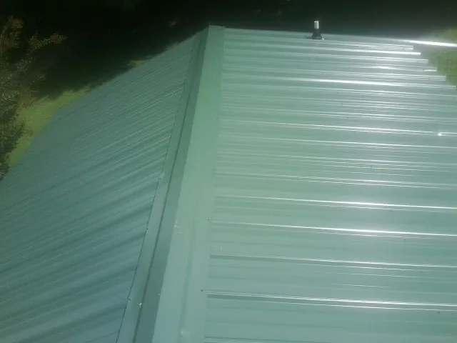 New green metal panels meeting at the ridge of a roof — Flat Roof Repair work by our crew in Nellysford