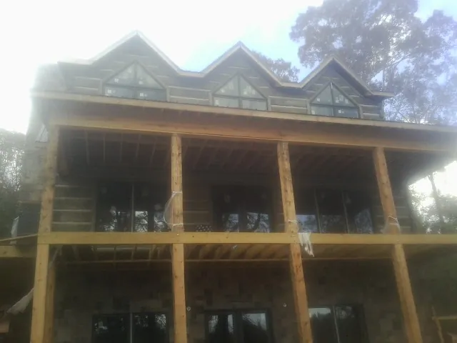 Dormers and porch framing on a large log home under construction — Roof Coating work by our crew in Nellysford