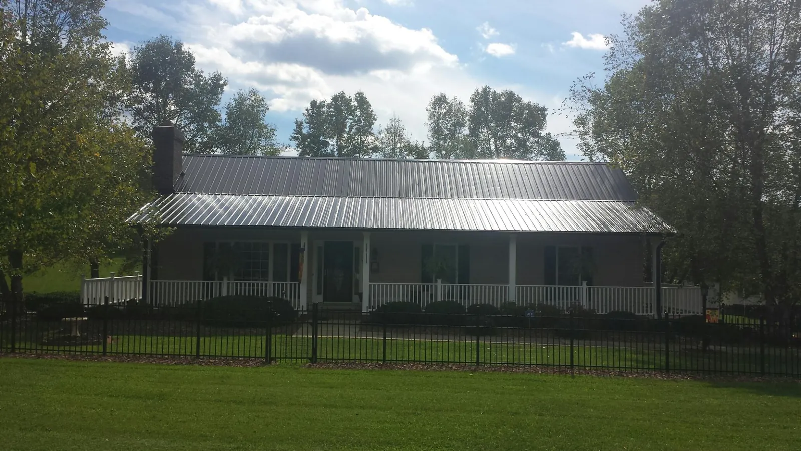 Gray metal roof on a brick ranch with a full width front porch — Gutter Guard Installation work by our crew in Nellysford