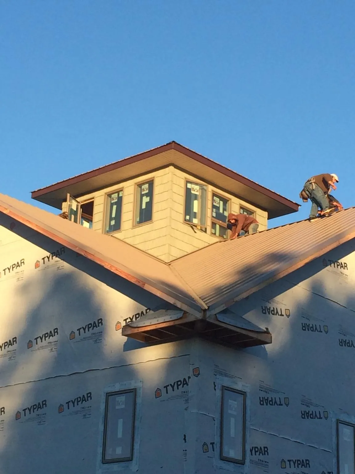 Roofers working around a rooftop cupola on a new metal roof at sunset — Roof Waterproofing in Nellysford by Roofing Brothers